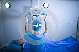 Nurse adjusting x-ray machine over patient