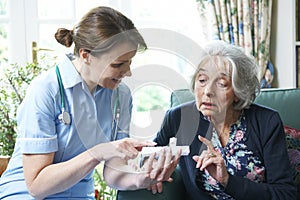 Nurse Advising Senior Woman On Medication At Home photo