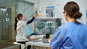 Nurse analysing digital x-ray sitting in front of pc