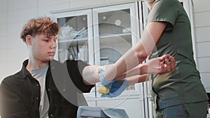 Nurse applies bandage carefully to arm of man patient to cover blood collection site