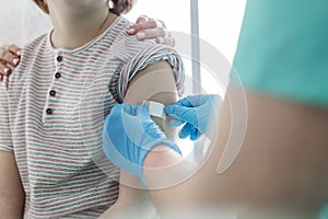 Nurse applying bandage on boy arm at hospital