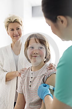 Nurse applying bandage on boy arm with mother at hospital