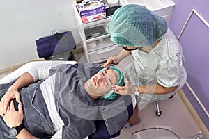 Nurse applying cream to a client to getting a facial beauty treatment