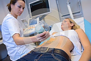 Nurse applying jelly to patient`s abdomen for ultrasound