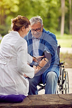 Nurse assessment of blood pressure elderly man in wheelchair