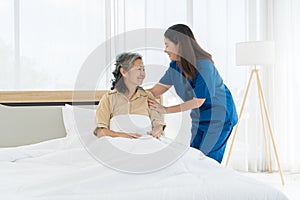 Nurse assistant concept. A woman in a blue uniform is helping an elderly woman in bed