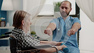 Nurse assisting disabled patient with physical exercises for recovery