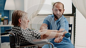 Nurse assisting disabled patient with physical exercises for recovery