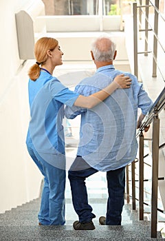Nurse assisting elderly man on stairs