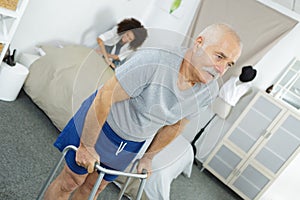 Nurse assisting elderly man with walking frame