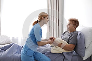 Nurse assisting elderly woman in bed