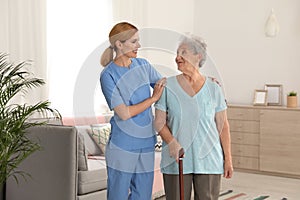 Nurse assisting elderly woman with cane