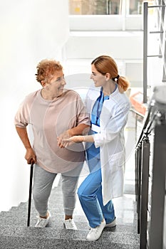 Nurse assisting elderly woman on stairs