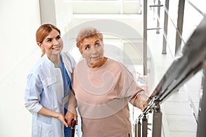 Nurse assisting elderly woman on stairs