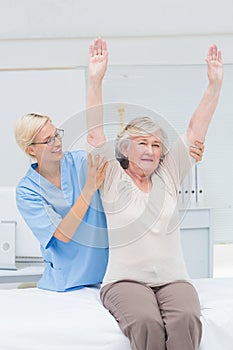 Nurse assisting female patient in exercising