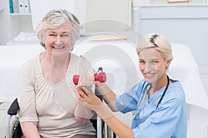 Nurse assisting female patient in lifting dumbbell