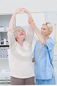 Nurse assisting female patient in raising arms