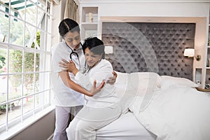 Nurse assisting patient on bed at home