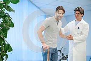 Nurse assisting a patient to walk with a stick