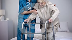 Nurse assisting patient walking frame, hip joint replacement rehabilitation