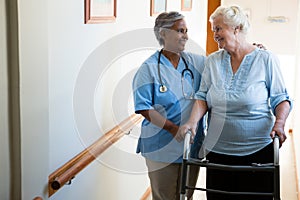 Nurse assisting patient in walking with walker at retirement home