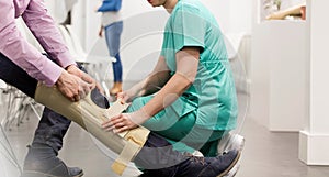 Nurse assisting patient in wearing knee brace at hospital