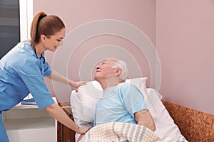 Nurse assisting senior man on bed