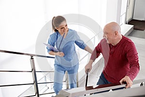 Nurse assisting senior man with cane to go up stairs