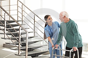 Nurse assisting senior man with walker