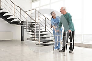 Nurse assisting senior man with walker