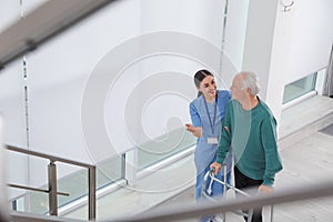 Nurse assisting senior man with walker