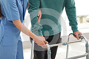 Nurse assisting senior man with walker in hospital