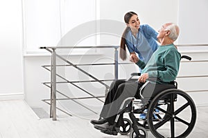 Nurse assisting senior man in wheelchair