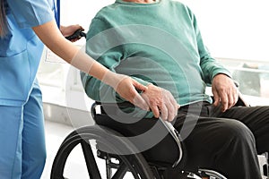 Nurse assisting senior man in wheelchair at hospital