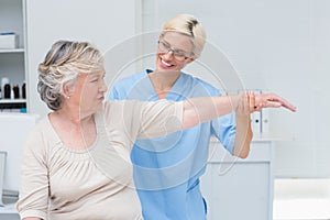 Nurse assisting senior patient in exercising at clinic