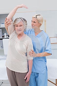 Nurse assisting senior patient in raising arm