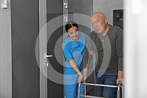 Nurse assisting senior patient with walker