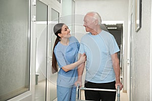 Nurse assisting senior patient with walker