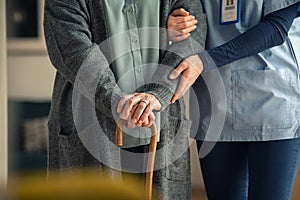 Nurse assisting senior with walking cane