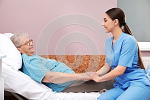 Nurse assisting senior woman lying on bed