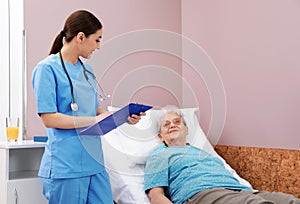 Nurse assisting senior woman lying on bed