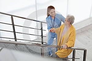 Nurse assisting senior woman to go up stairs