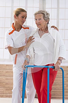 Nurse Assisting Senior Woman To Walk With Zimmer