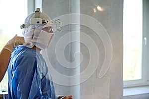 A nurse assists the chief surgeon in putting on a protective uniform