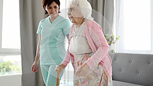 Nurse Assists Elderly Woman Moving Around Room