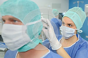 Nurse assiting to secure mask on colleague