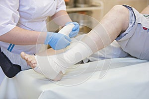 Nurse bandages the leg.
