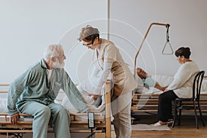 Nurse in a beige uniform helps the patient in a blue pajamas getting up from bed