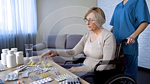 Nurse bringing senior lady in wheelchair to table for taking medicine, treatment