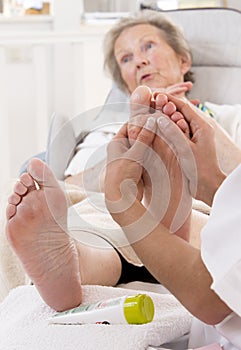 Nurse or care giver treating a senior woman's foot